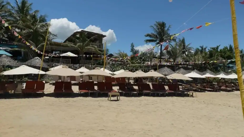 Hoi An beaches featuring An Bang Beach with sun loungers white umbrellas and tropical palm trees lining shore