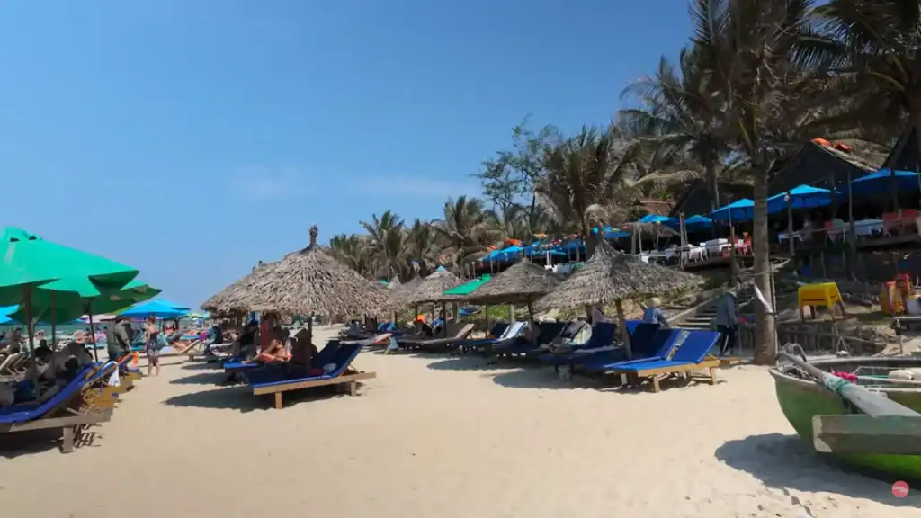 An Bang Beach with sun loungers thatched umbrellas and palm trees under blue sky