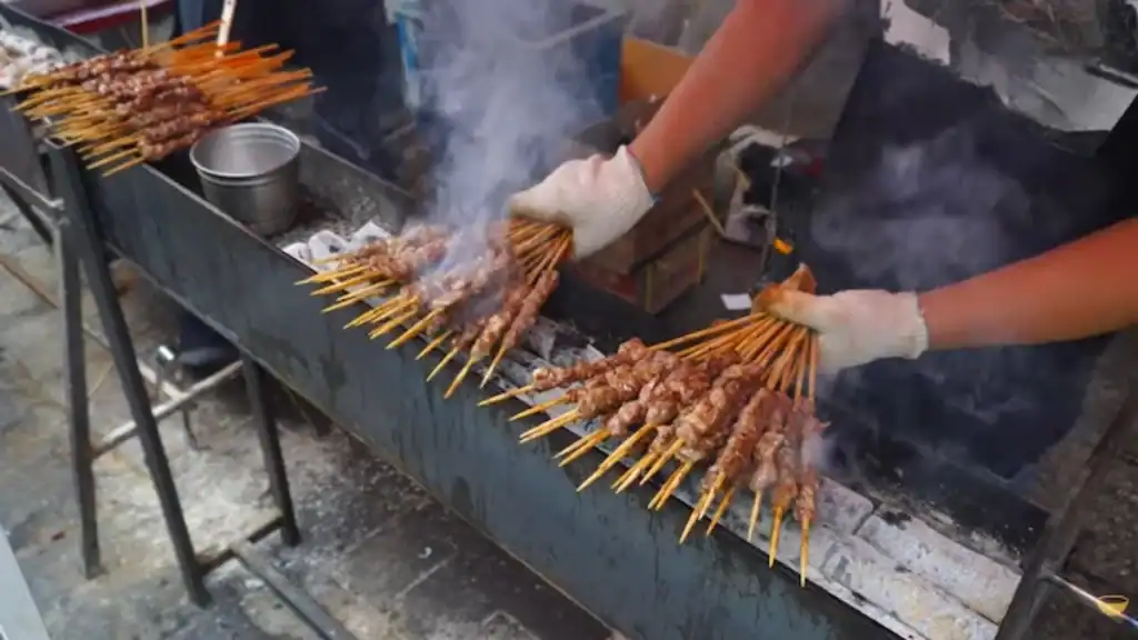 Lamb skewers grilling on charcoal at Ansan markets with smoke rising from outdoor barbecue