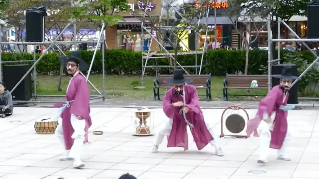 Traditional Korean performers in purple hanbok playing drums at outdoor cultural performance near Ansan markets