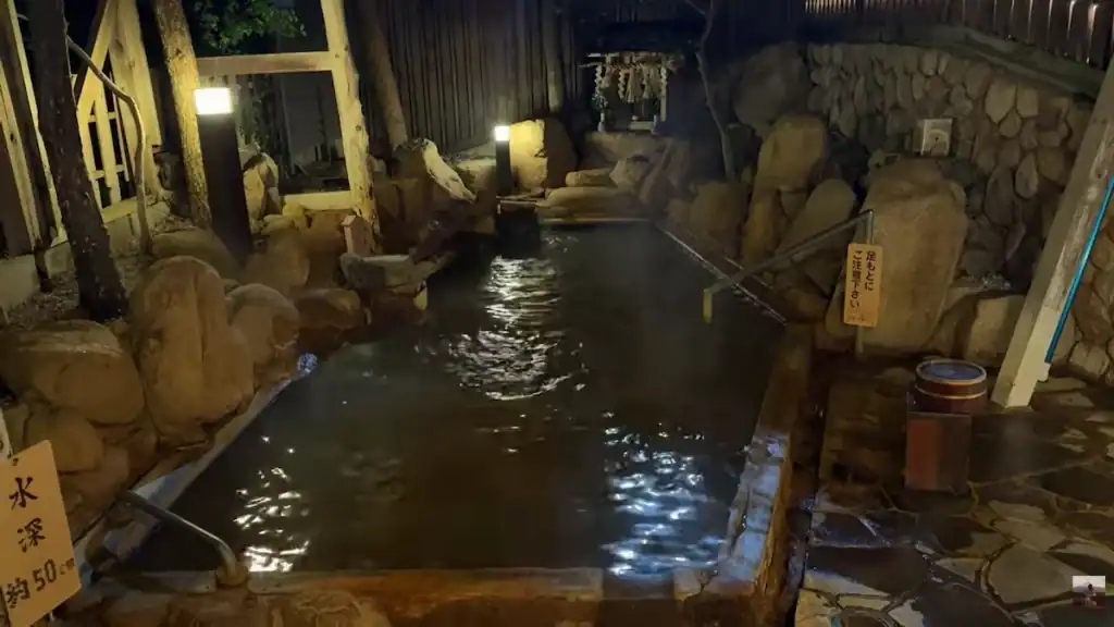 is Kinosaki Onsen worth it - Arima Onsen hot spring bath with natural rock features at night