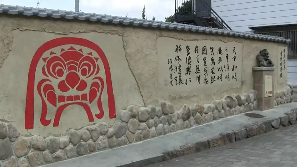 Kinosaki vs Arima - red demon mask mural on stone wall in historic Arima Onsen town