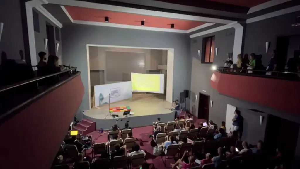 Bansko digital nomad attending presentation at Nomad Fest conference in modern theater venue