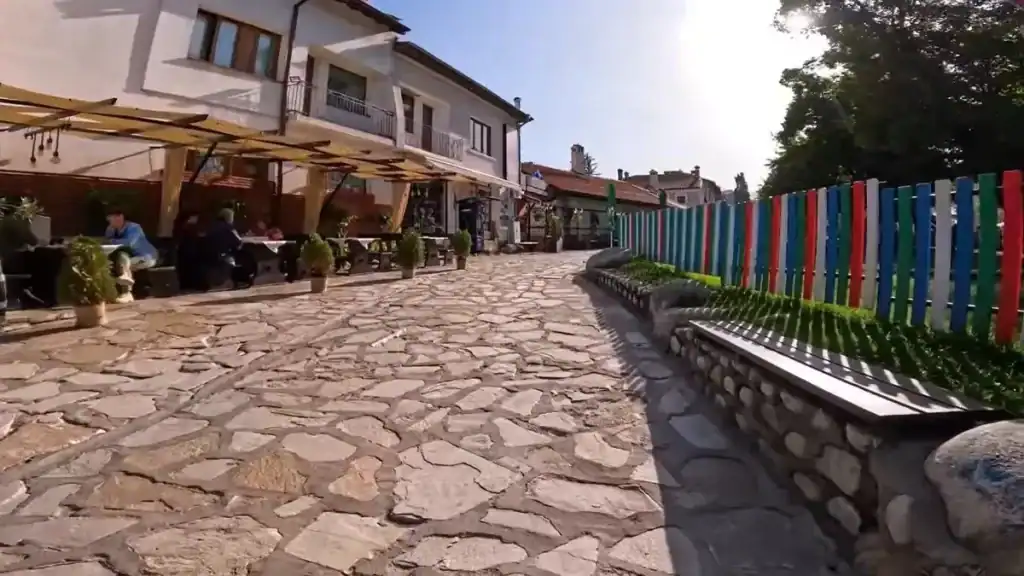 Bansko summer vs winter stone plaza with outdoor cafes and colorful fence