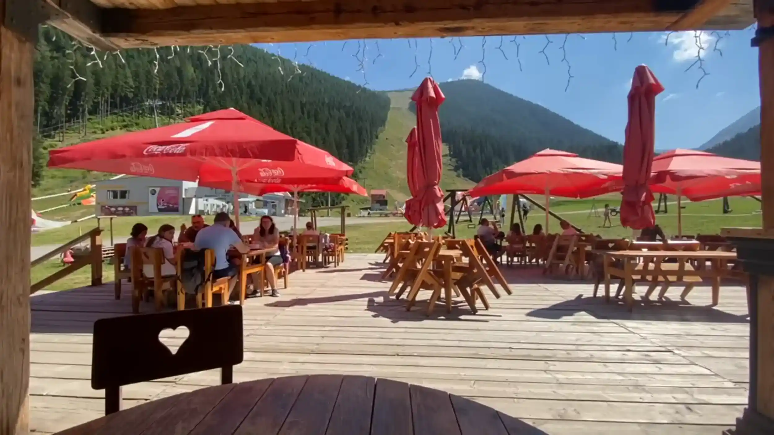 Bansko summer vs winter mountain terrace with red umbrellas and dining guests