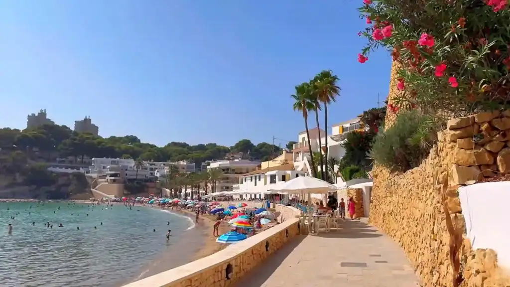 Moraira expensive beachfront promenade with coastal restaurants and luxury hillside properties.