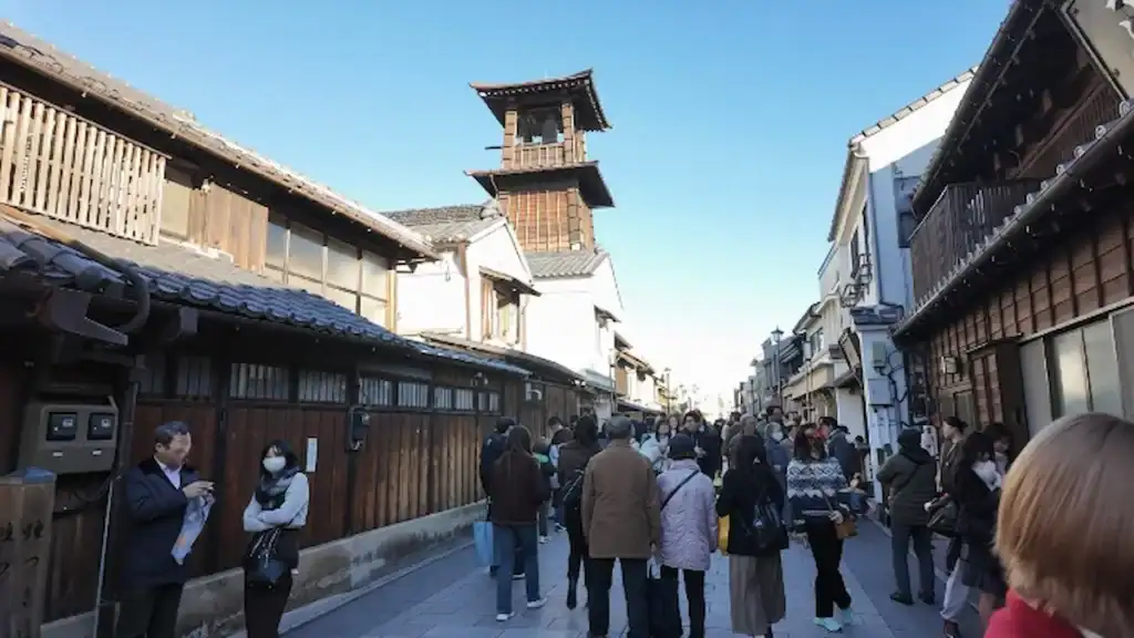 Kawagoe's iconic wooden bell tower rising above crowded street lined with traditional merchant buildings