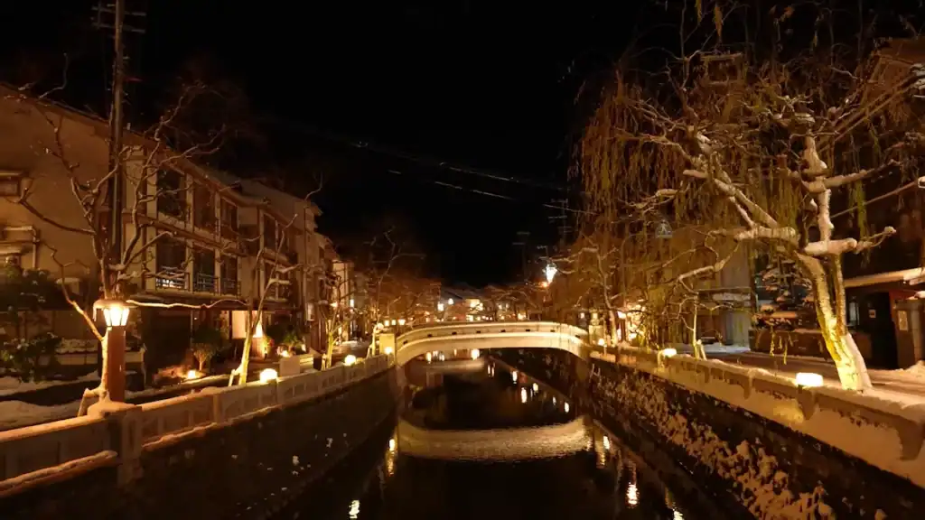one night in Kinosaki Onsen - illuminated bridge over canal with traditional ryokans at night
