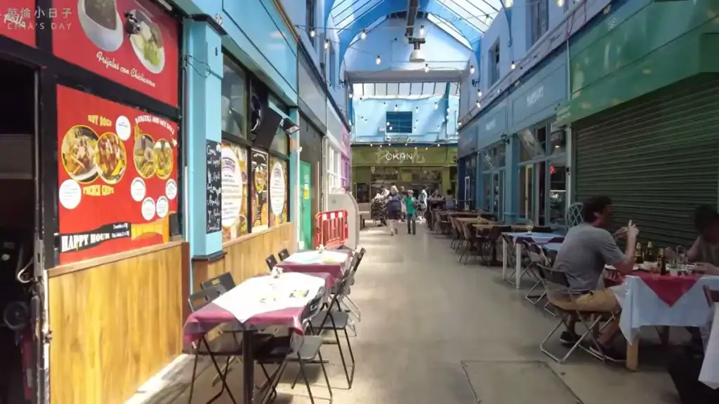 Brixton Village covered market with colorful storefronts and dining tables