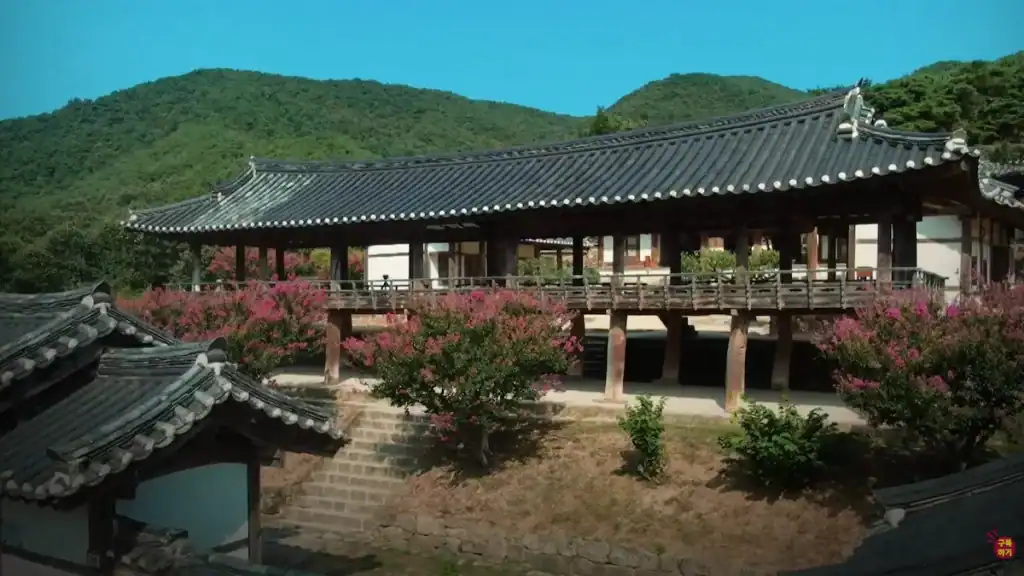 Andong cultural experience Byeongsan Seowon Confucian Academy with elevated wooden pavilion pink flowering trees and mountains in background