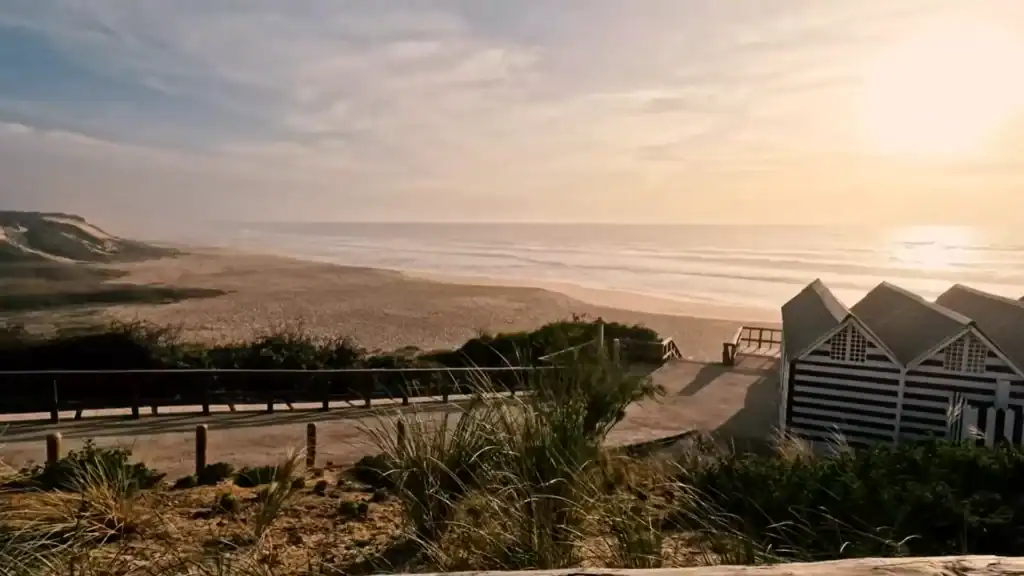 Comporta beach late afternoon with striped cabanas and golden sunset light over Atlantic