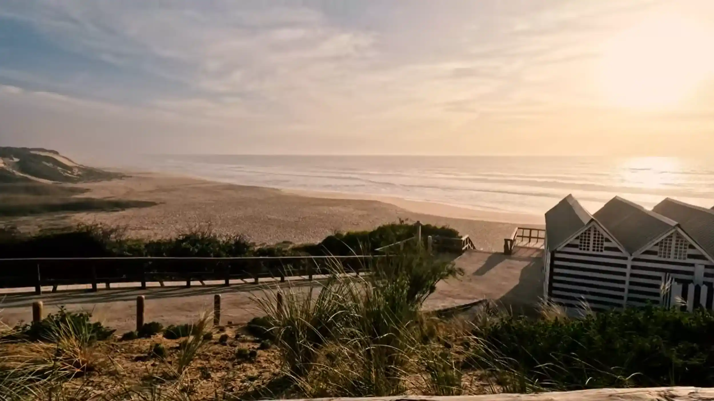 Comporta beach late afternoon with striped cabanas and golden sunset light over Atlantic