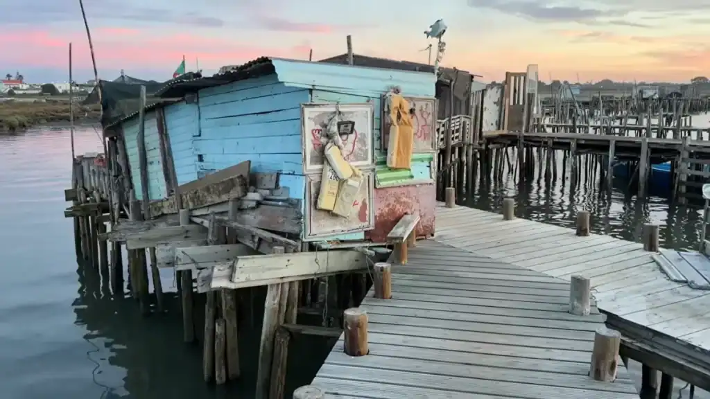 Old wooden jetty with traditional fishing huts at sunset over calm waters