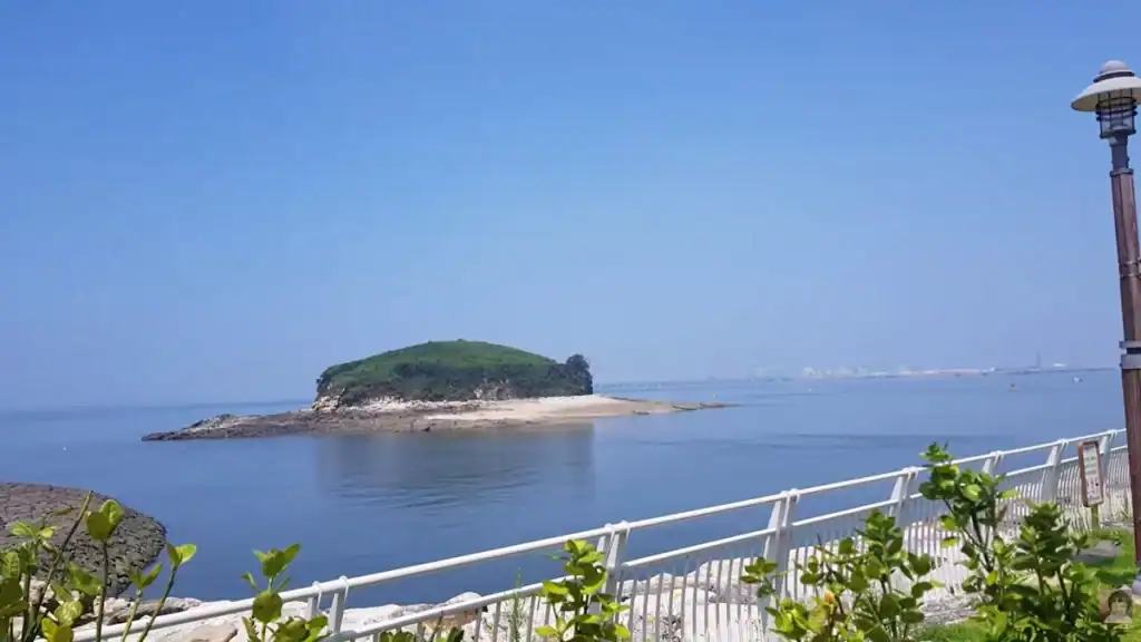 Daebudo Island near Sihwa Tidal Power Plant with small green island, sandy beach, calm blue waters, and observation tower visible on coastline