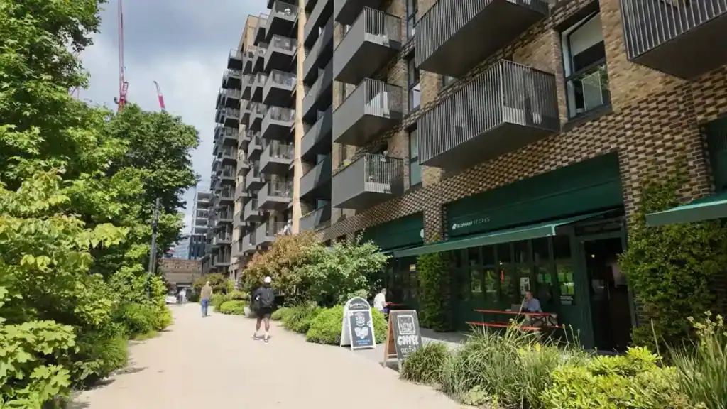Coffee shop with green awning beside landscaped walkway and apartment buildings