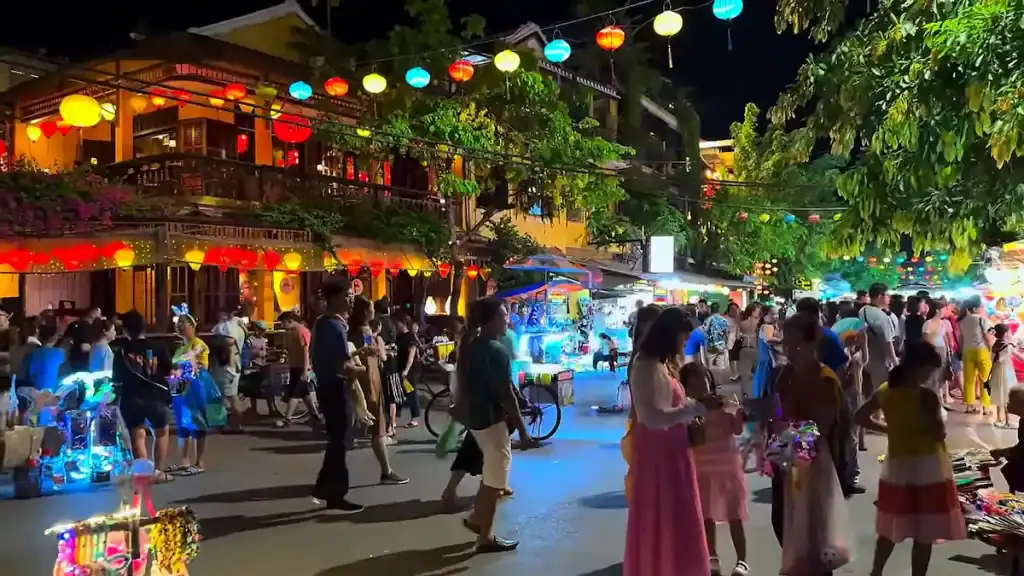 Night market crowds and lanterns showcase popular tourist area versus cheap alternative to Hoi An
