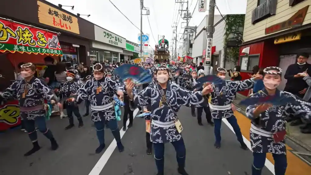 Dancers in matching black and white patterned yukata performing with fans on street during Sawara Grand Festival