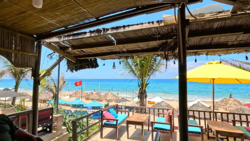 Beachfront restaurant with ocean views at Hoi An beaches featuring thatched roof and turquoise cushioned seating area