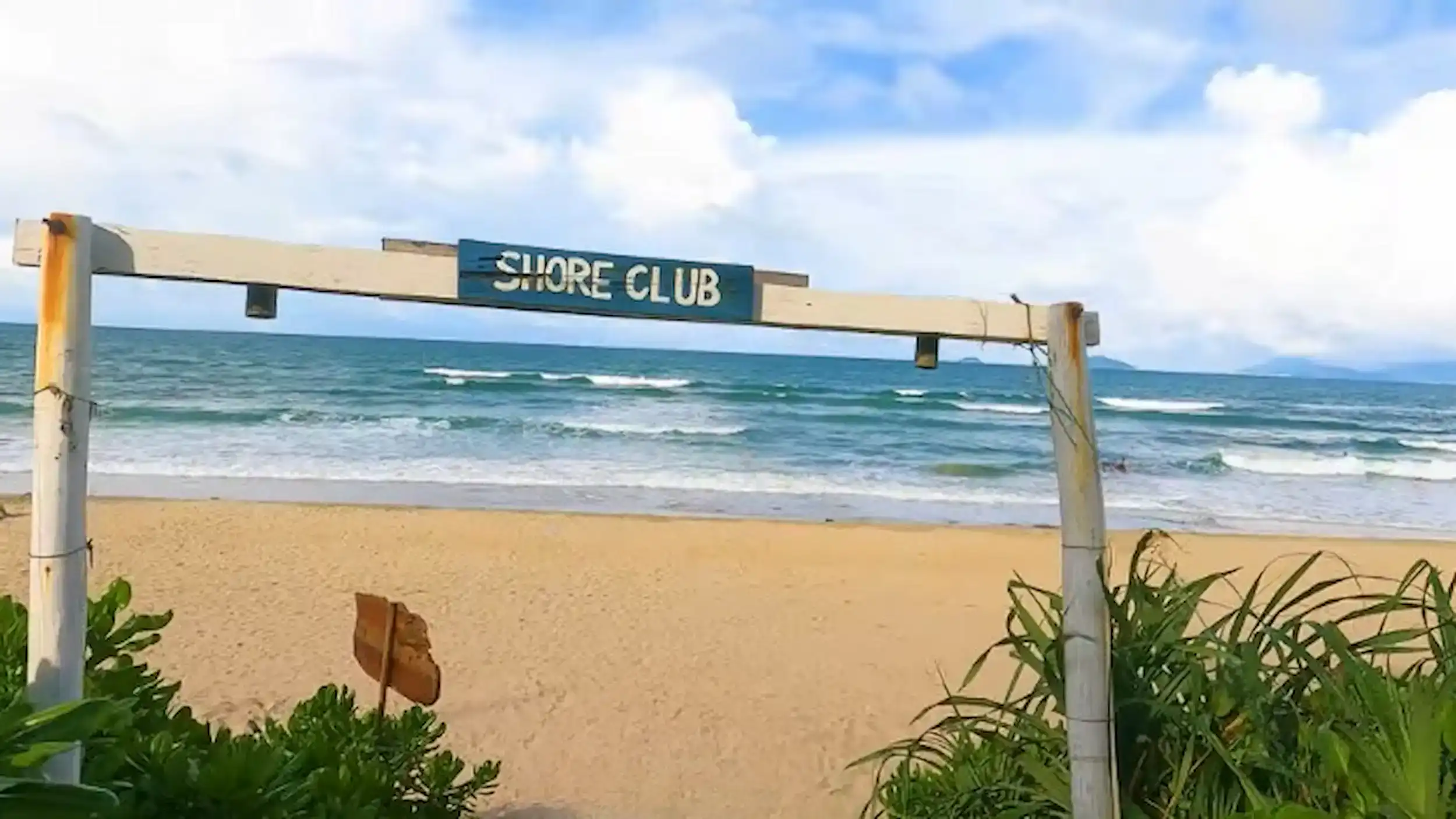 Shore Club entrance sign frames the scenic view of Hoi An beaches with golden sand and turquoise waves