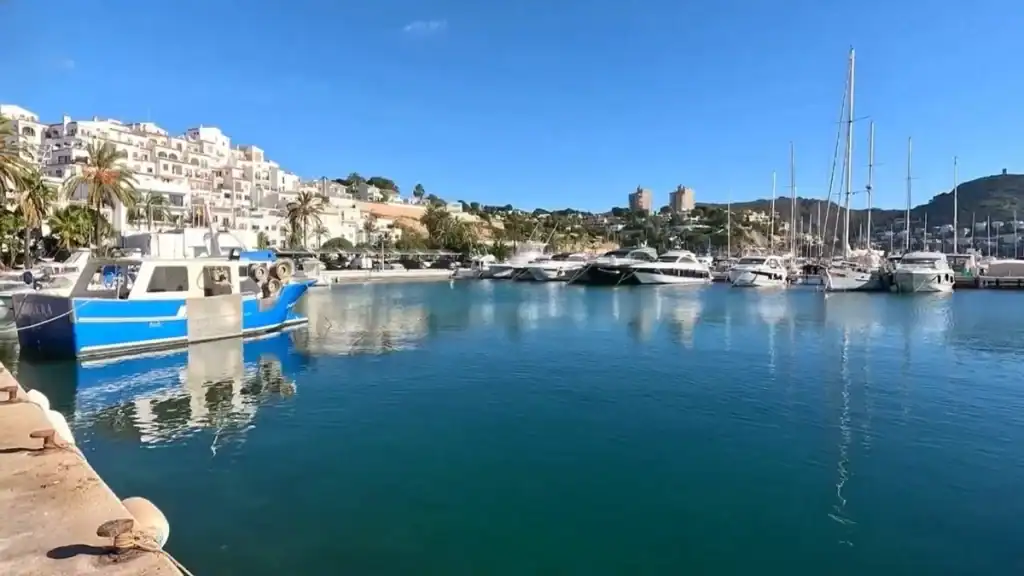 Marina walk with calm blue waters with moored boats and yachts.