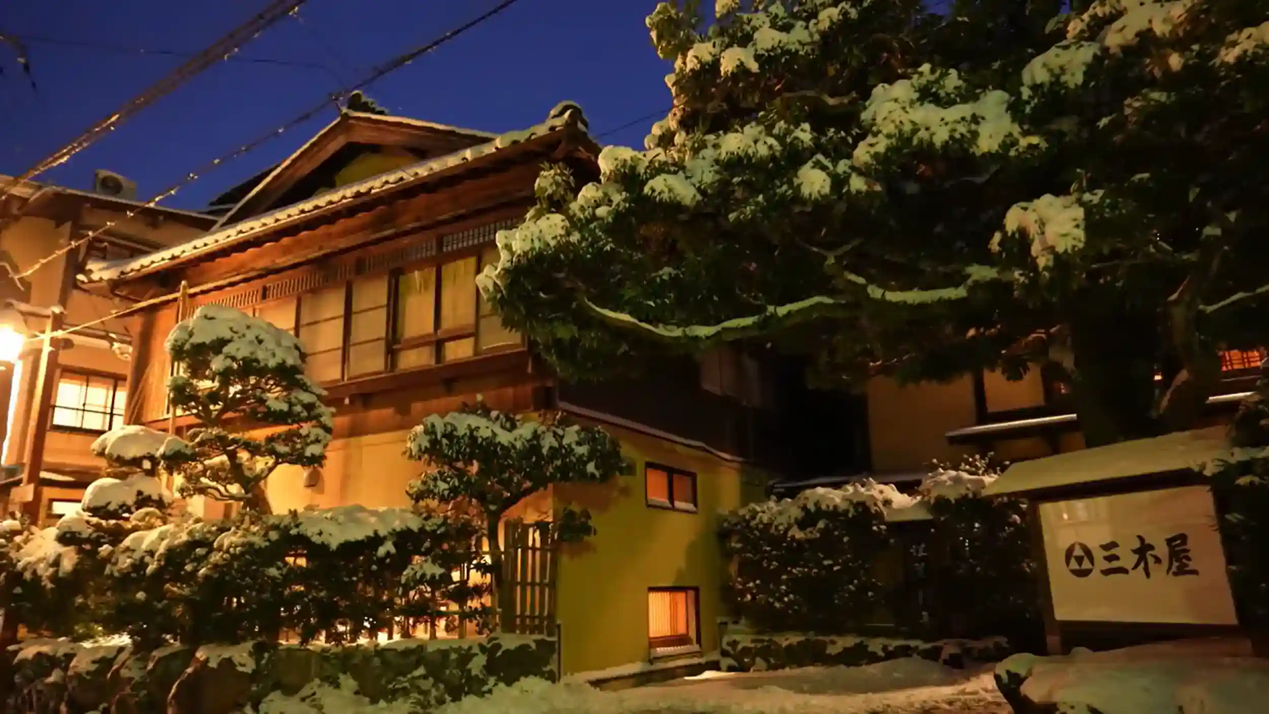 Mikiya inn illuminated at night with snow-covered pine trees