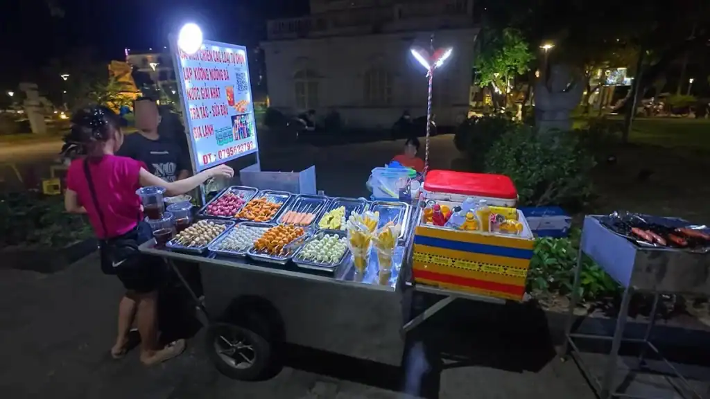Night street vendor cart selling various snacks