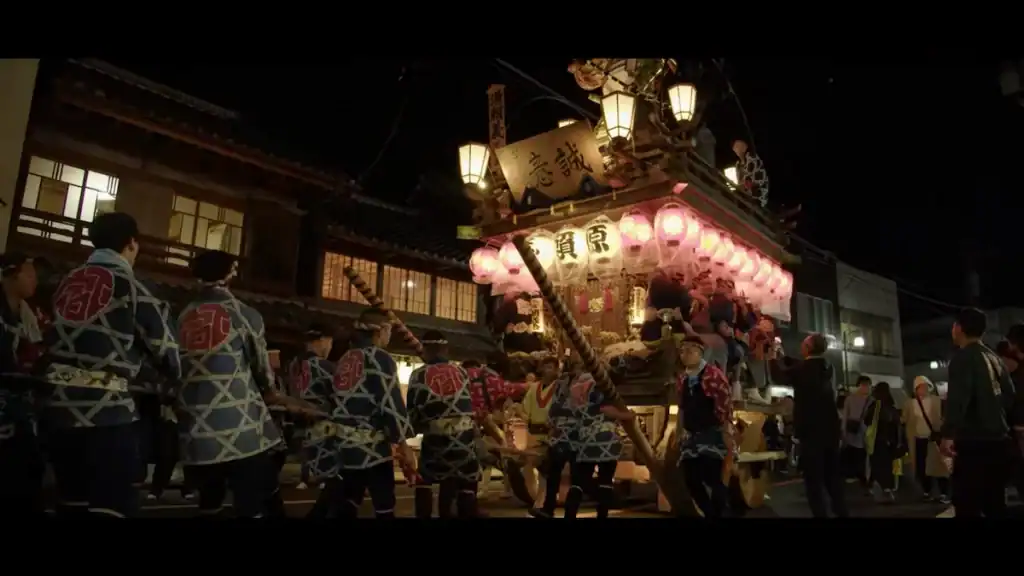 Men in traditional festival clothing pulling illuminated float with paper lanterns at Sawara Grand Festival