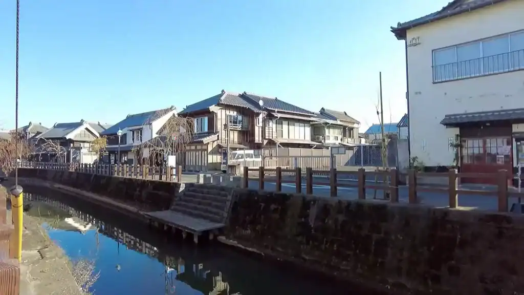 Traditional merchant houses reflected in calm canal waters with wooden docks in Sawara, Japan