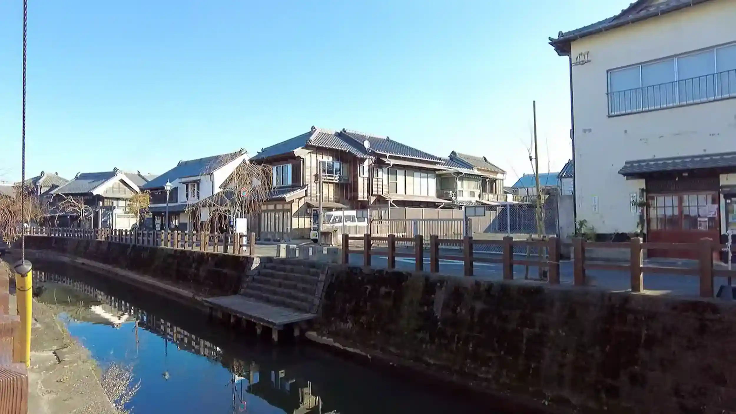 Traditional merchant houses reflected in calm canal waters with wooden docks in Sawara, Japan
