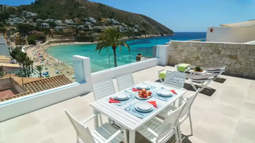 Self-catering villa terrace overlooking turquoise bay and sandy beach.