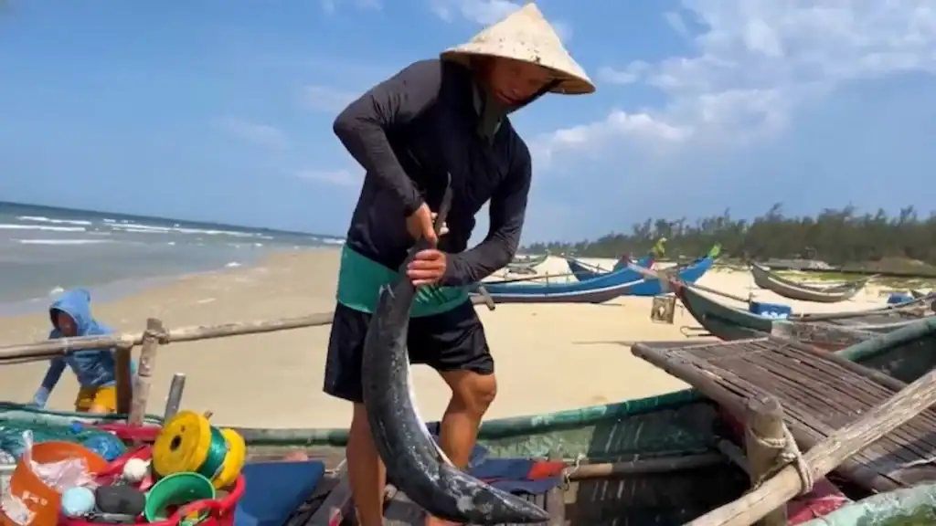 Local fisherman with fresh catch at Tam Thanh Beach illustrating authentic life in Tam Ky vs Hoi An