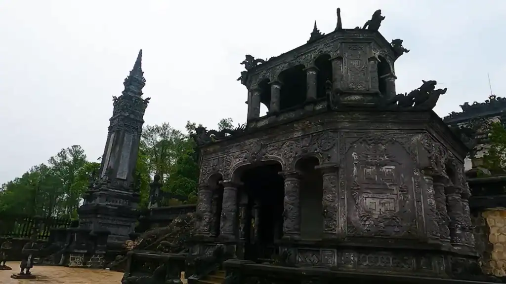 Ancient imperial tomb with ornate dragon carvings under Hue's rainy season skies