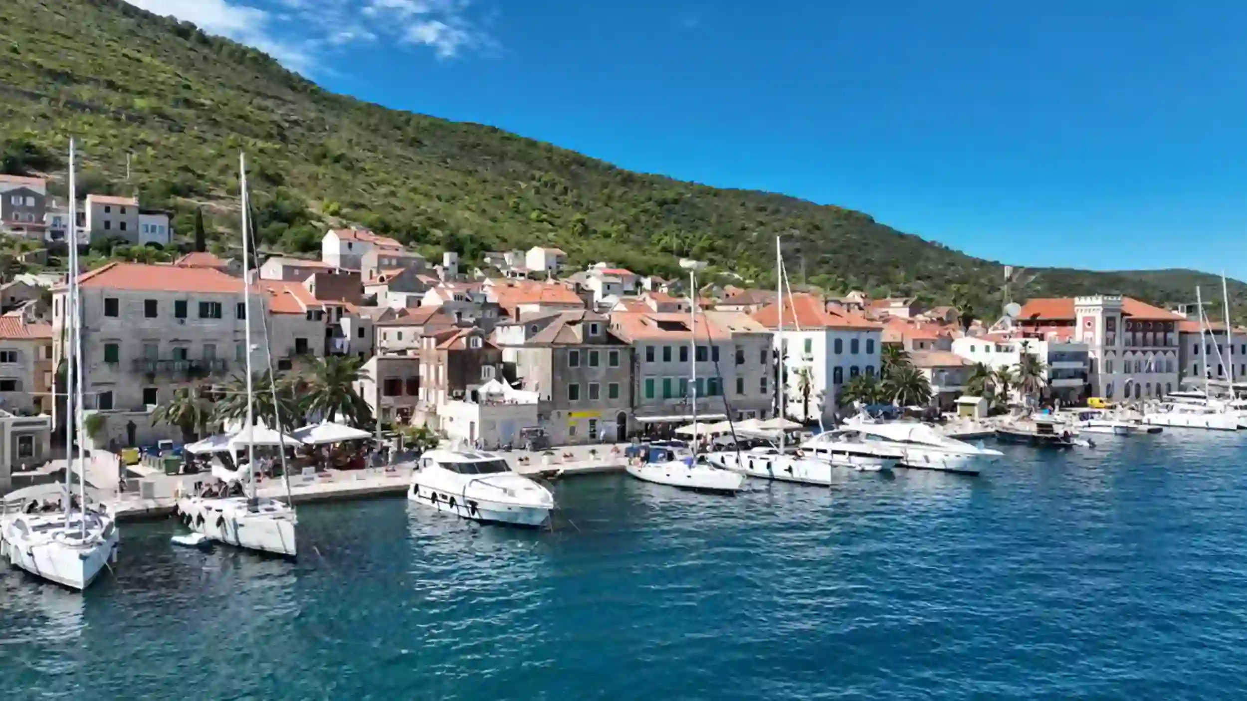 Vis Town vs Komiza waterfront with yachts moored in turquoise harbour waters
