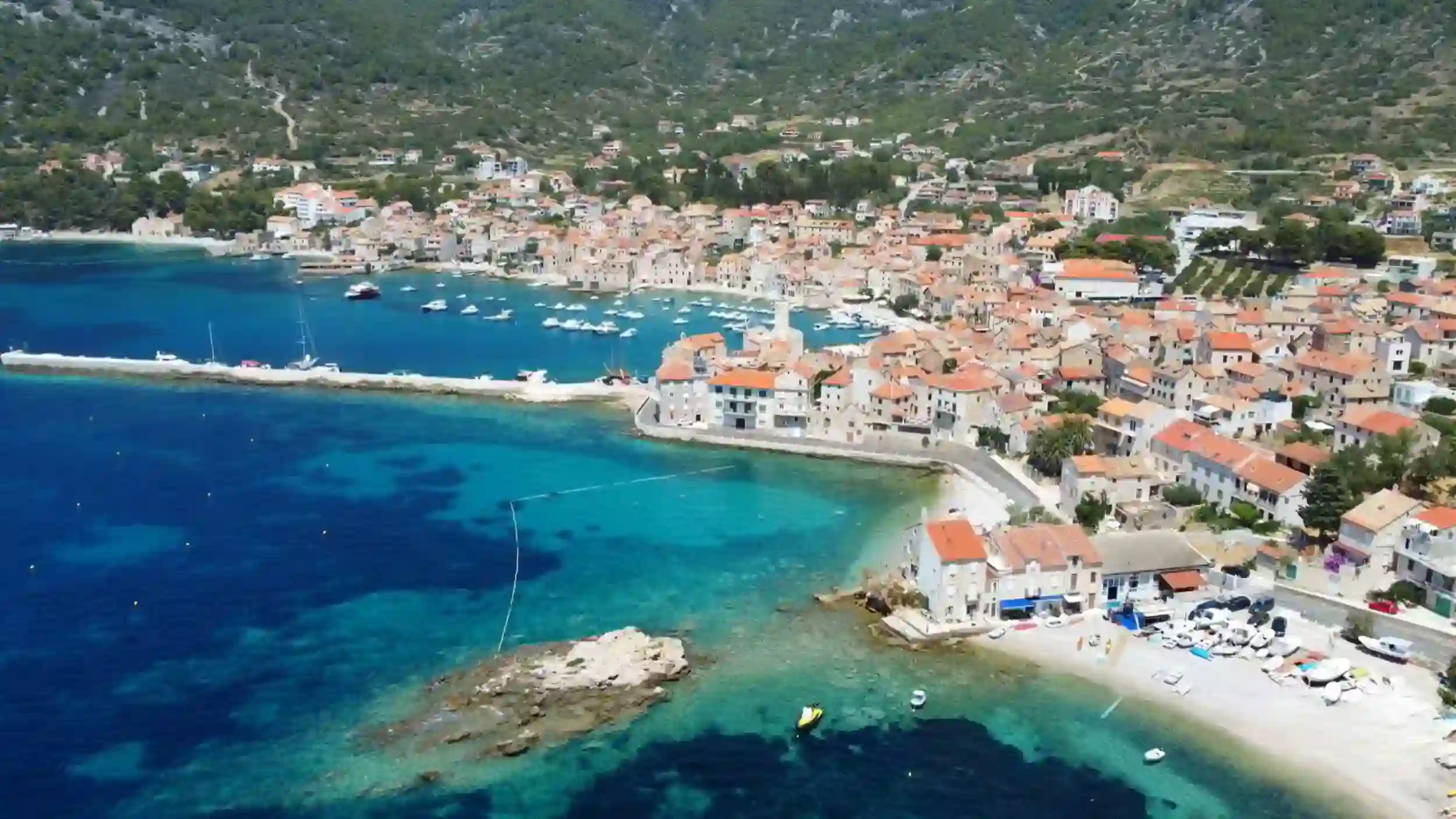 Vis Island without a car aerial view showing compact harbor town with terracotta roofs and turquoise bay