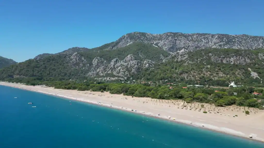 Çıralı quiet alternative showcasing expansive beach with turquoise waters and mountain scenery