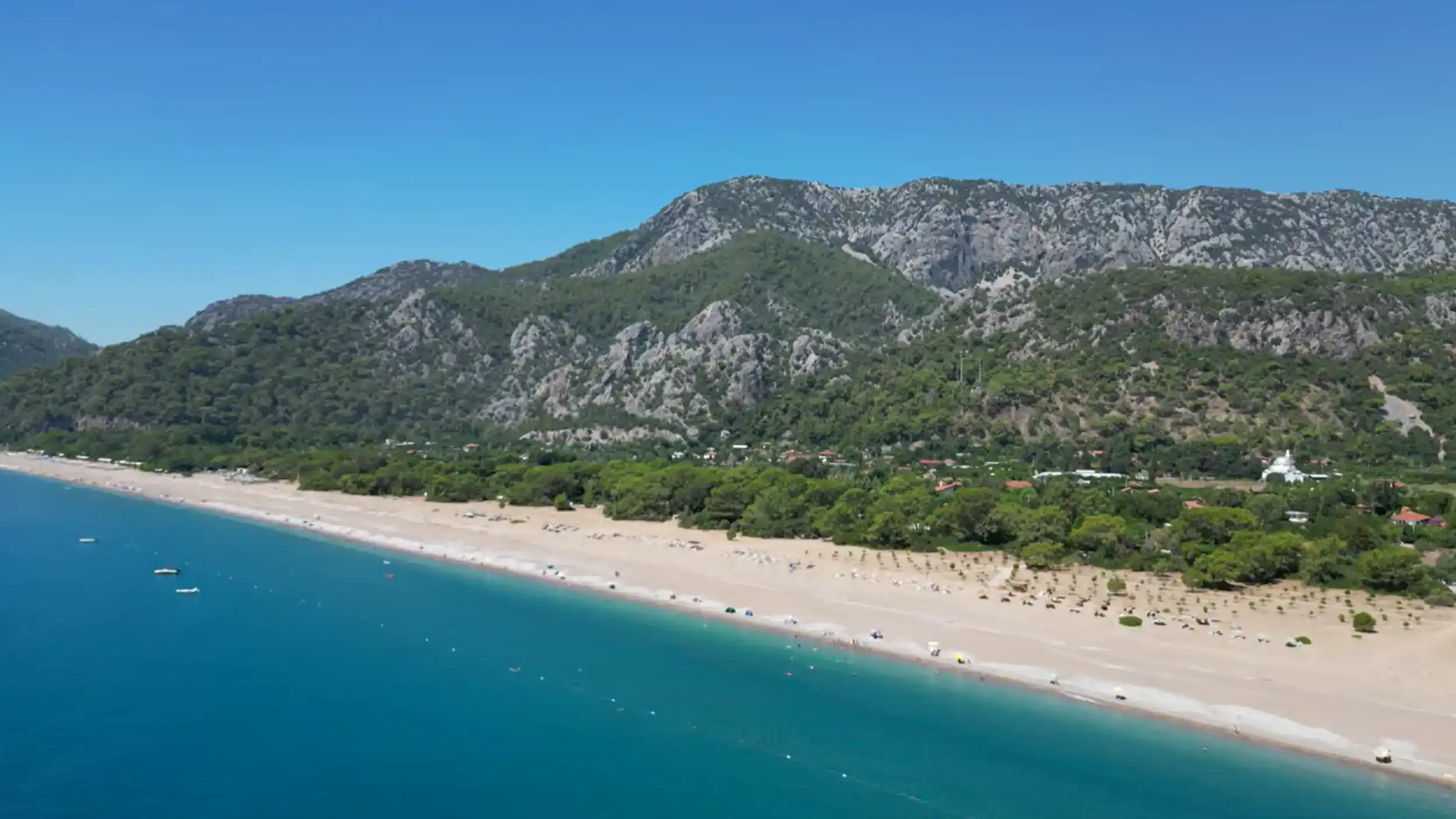 Çıralı quiet alternative showcasing expansive beach with turquoise waters and mountain scenery
