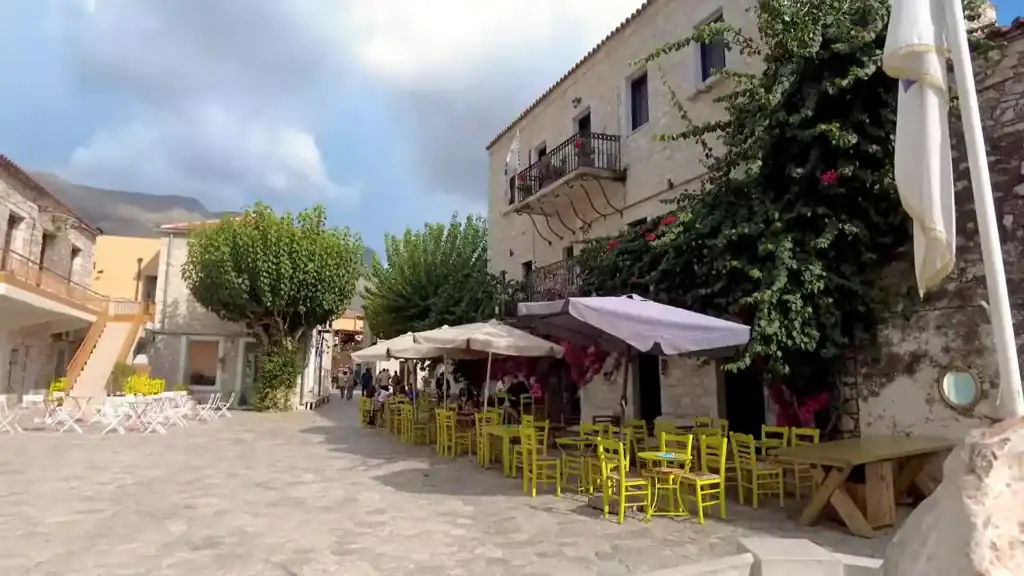 Outdoor café tables with bright yellow chairs filling Areopoli's cobbled main square