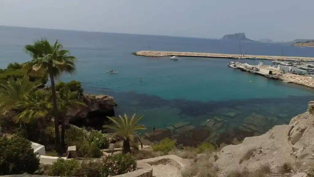 Moraira vs Calpe coastal cove with turquoise waters and small marina.