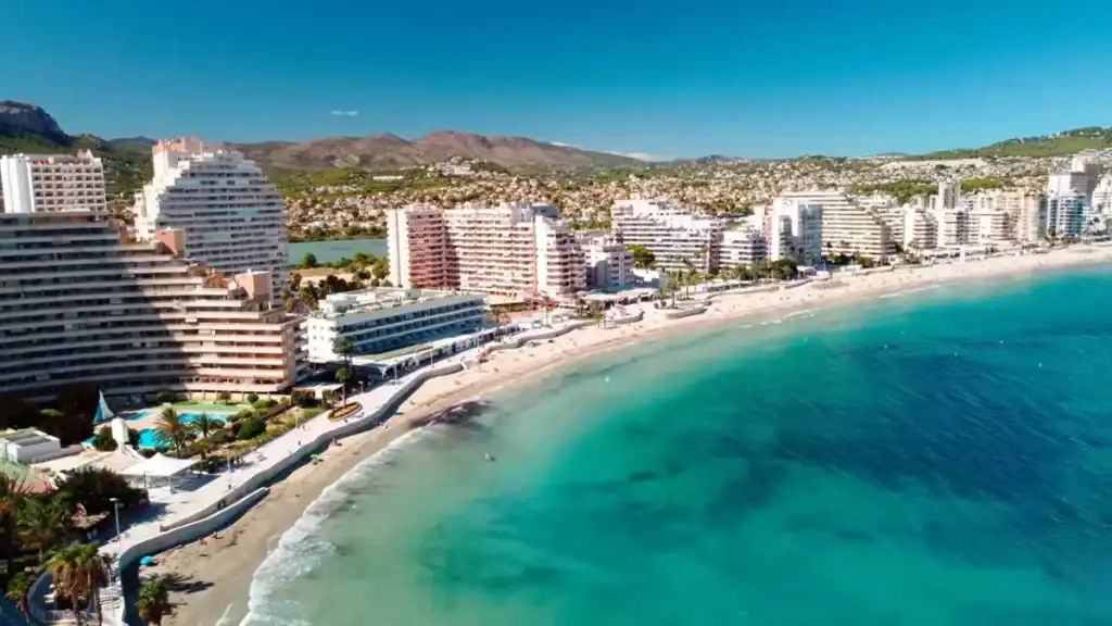 Moraira vs Calpe resort scene with beachfront hotels and turquoise sea.