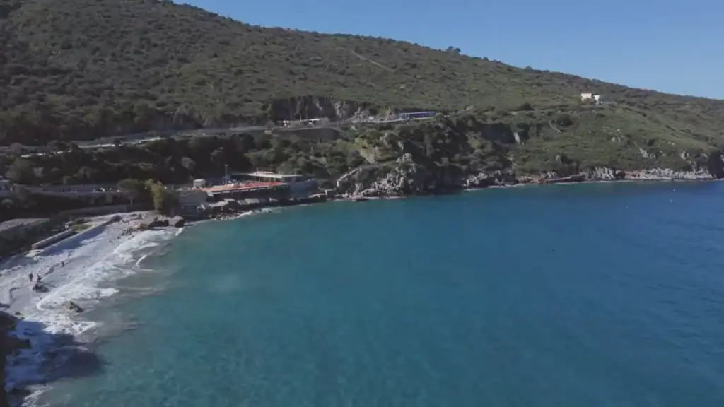 Aerial view of Diros Caves Mani Peninsula coastline with turquoise water curving against rocky cliffs and scrub-covered hills