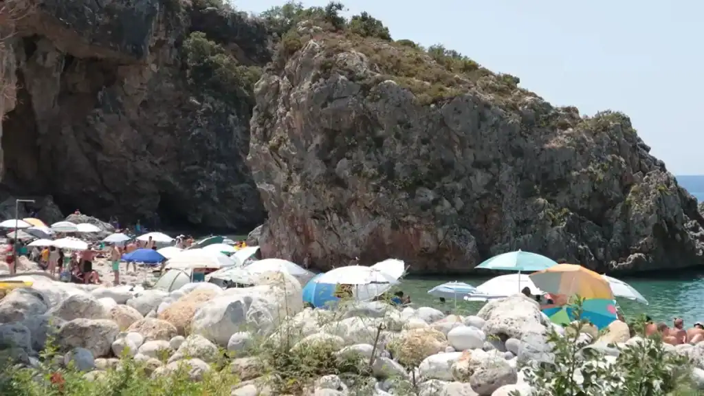 Scenic beach cove comparing Stoupa vs Kardamyli coastal destinations with umbrellas.