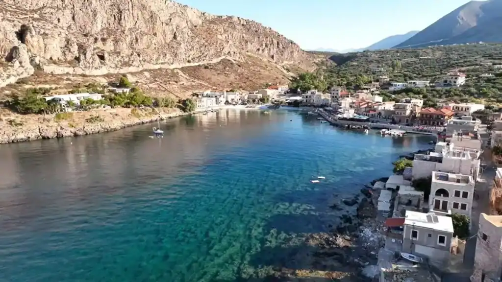 Aerial view of Gerolimenas harbour with deep blue water and stone buildings