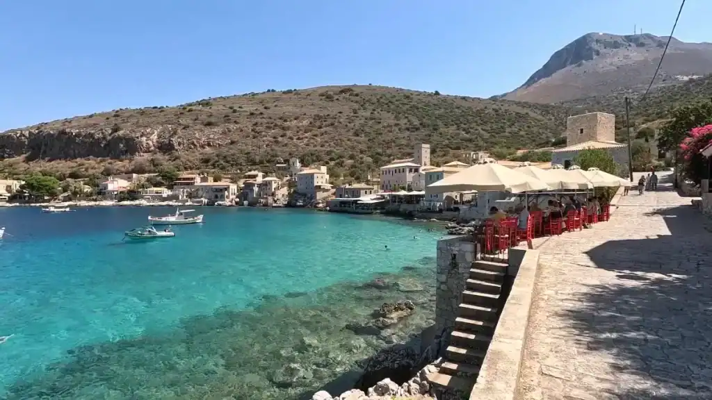Stone waterfront promenade at Limeni with turquoise bay and traditional village buildings