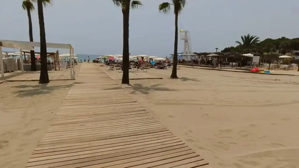 Moraira beaches offer wooden boardwalk access with palm trees and beach facilities.