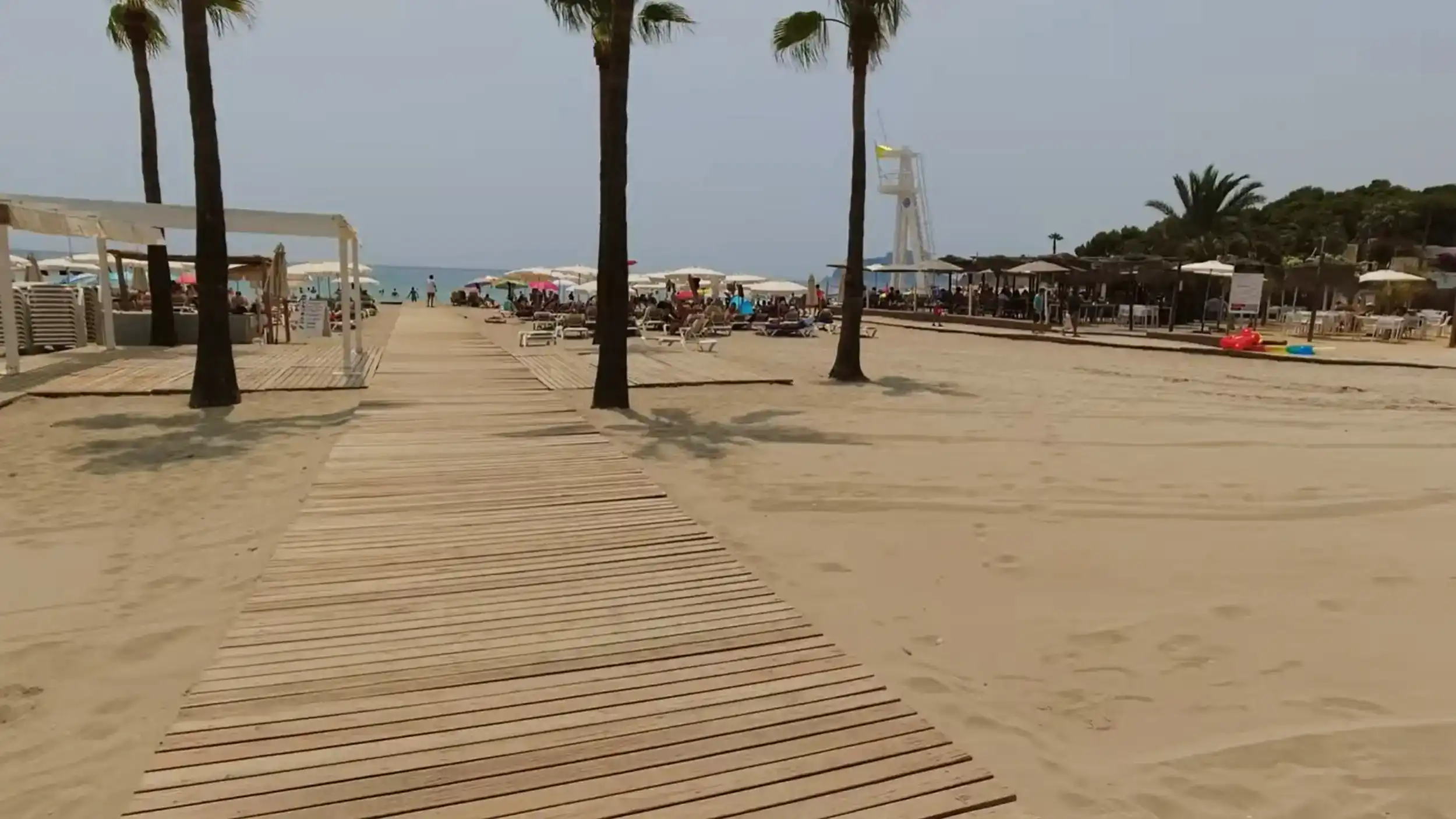 Moraira beaches offer wooden boardwalk access with palm trees and beach facilities.