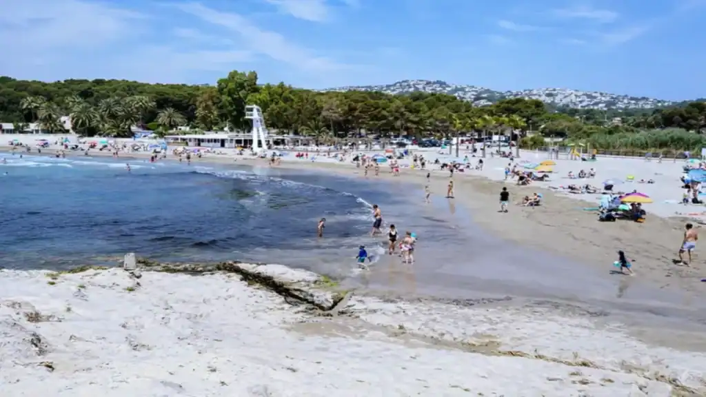 Playa l'Ampolla with families enjoying shallow waters and sand.