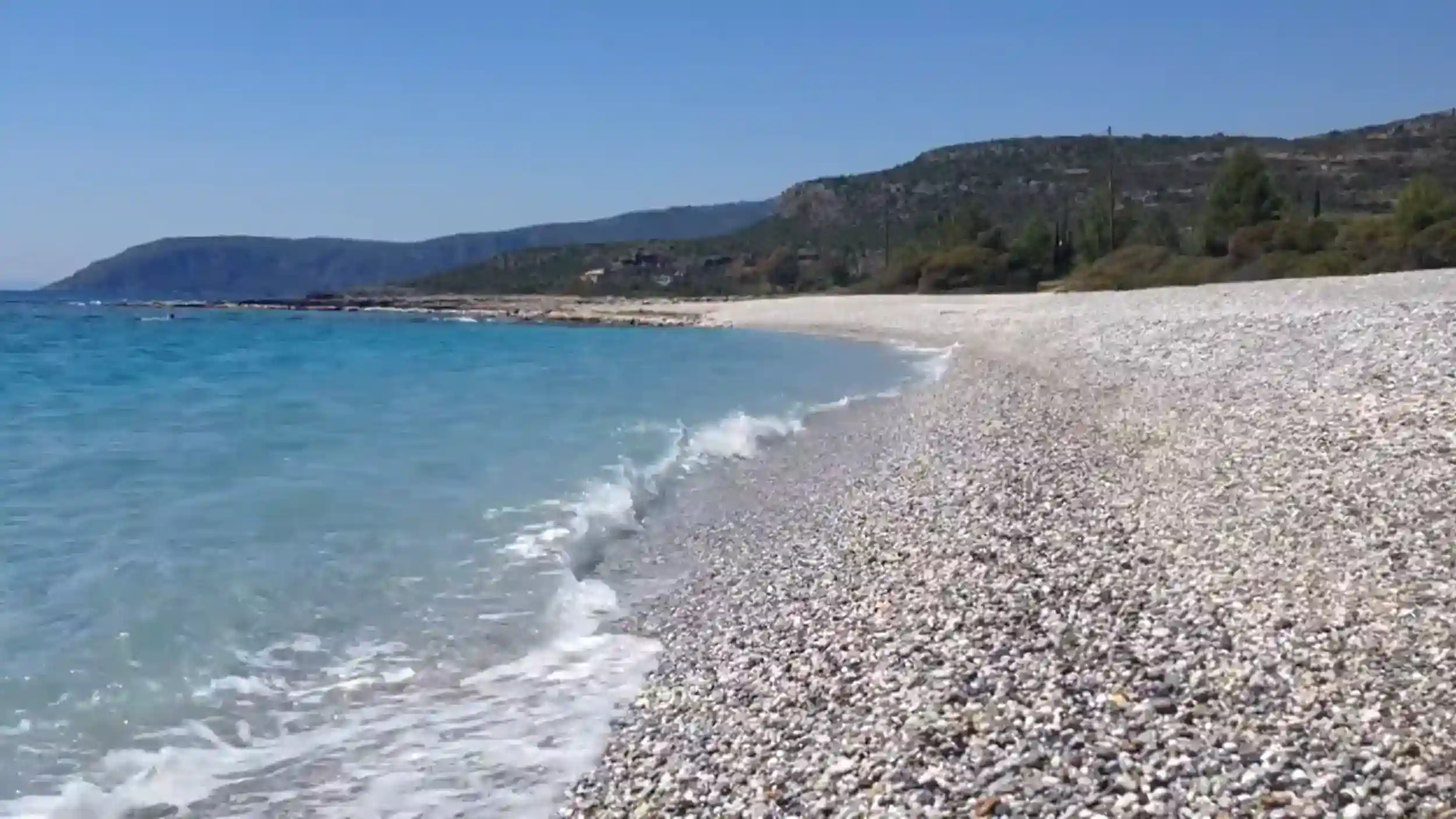 Kardamyli Beach with crystal clear turquoise waters and pebble shoreline.