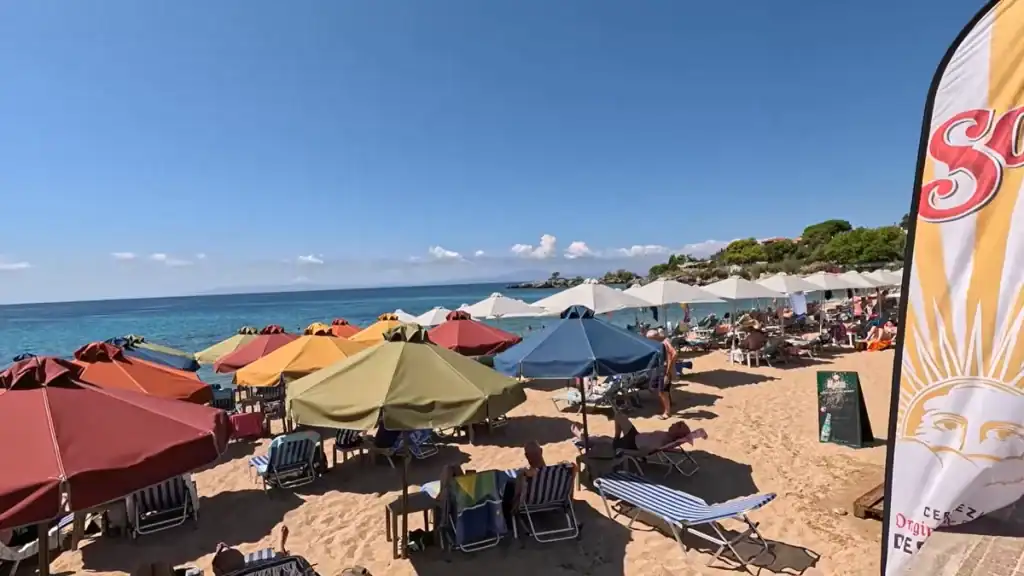 Mani Peninsula peace and quiet. Stoupa Beaches with colorful umbrellas and sunbathers enjoying Mediterranean waters.