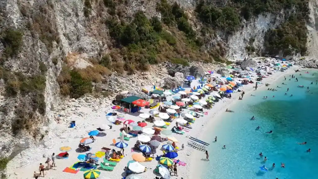 Agiofili packed with colourful umbrellas against a limestone cliff, among the more sheltered Lefkada beaches reached only by boat or a short footpath
