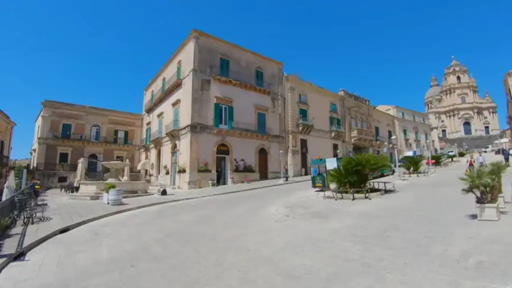 Ragusa Ibla travel starts here for many visitors - Piazza del Duomo opens across pale stone paving with the Cathedral of San Giorgio's ornate facade rising to the right